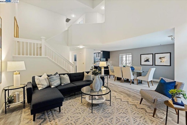 living room with hardwood / wood-style flooring and a towering ceiling