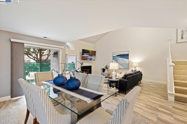 dining space with vaulted ceiling and light wood-type flooring