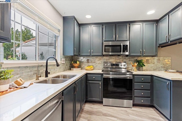 kitchen with sink, tasteful backsplash, appliances with stainless steel finishes, gray cabinets, and light stone countertops