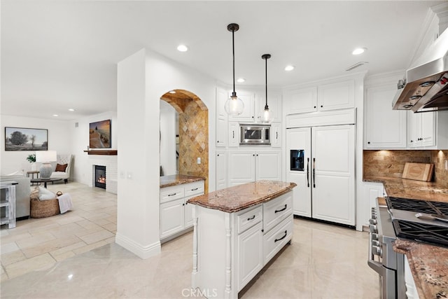 kitchen featuring pendant lighting, range hood, white cabinets, a center island, and built in appliances