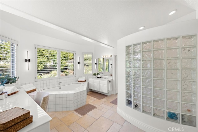 bathroom featuring vanity, tiled bath, and a textured ceiling