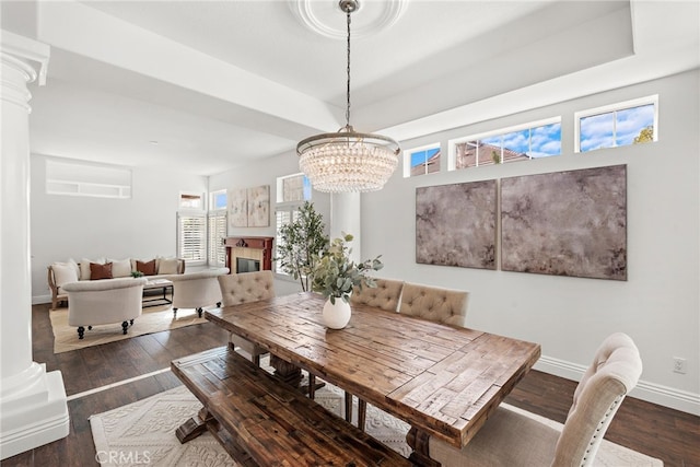 dining area featuring dark hardwood / wood-style flooring, decorative columns, and a raised ceiling