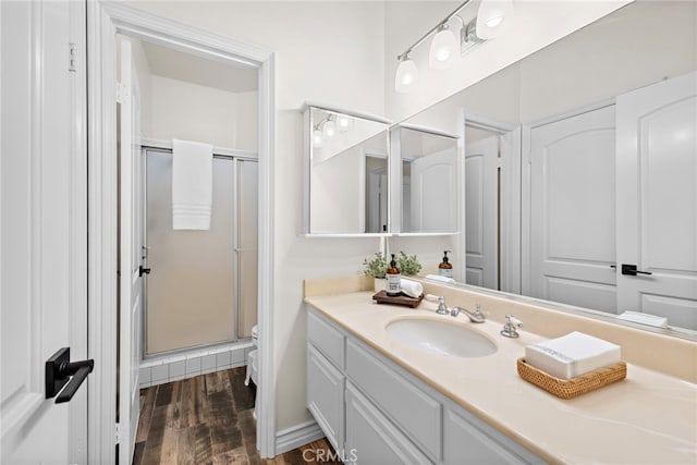 bathroom featuring a shower with door, vanity, hardwood / wood-style flooring, and toilet