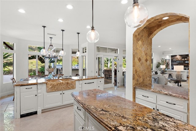 kitchen with white cabinetry, sink, decorative light fixtures, and a wealth of natural light