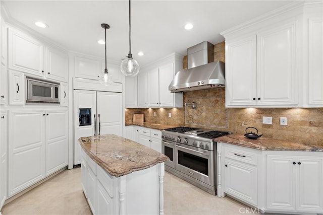 kitchen with built in appliances, white cabinets, decorative light fixtures, and wall chimney exhaust hood