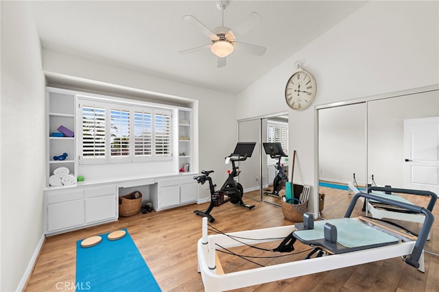 workout area featuring ceiling fan, vaulted ceiling, and light wood-type flooring