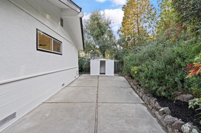 view of home's exterior with a patio area and a storage shed