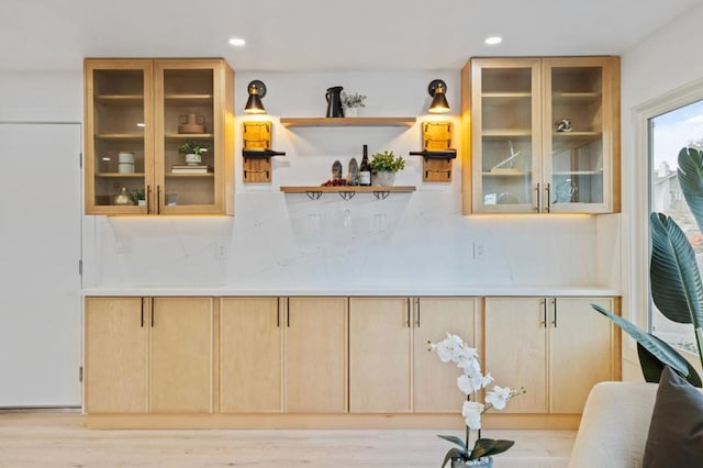 bar featuring light brown cabinets, backsplash, and light wood-type flooring