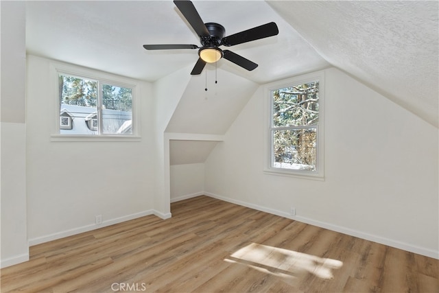 bonus room with lofted ceiling, a textured ceiling, and light hardwood / wood-style flooring