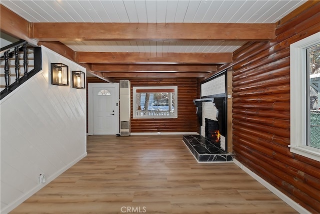 foyer entrance with log walls, beam ceiling, light hardwood / wood-style floors, and a healthy amount of sunlight