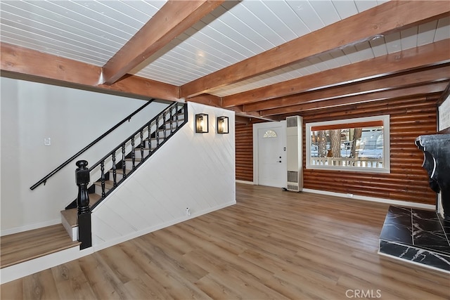 unfurnished living room featuring heating unit, beamed ceiling, wood-type flooring, rustic walls, and wooden ceiling