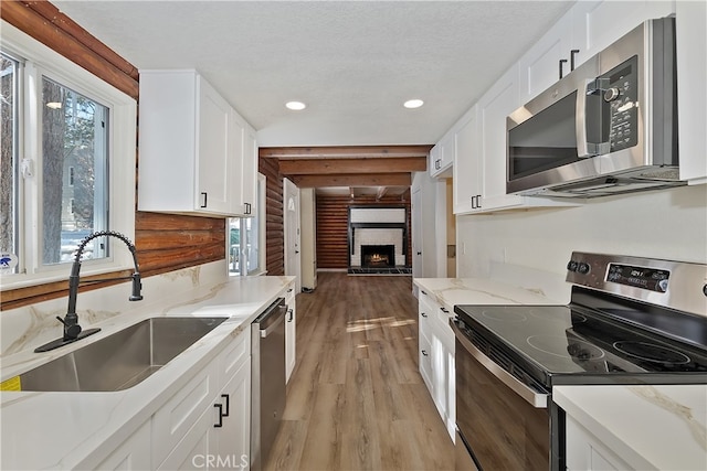 kitchen featuring white cabinetry, sink, stainless steel appliances, and light stone countertops