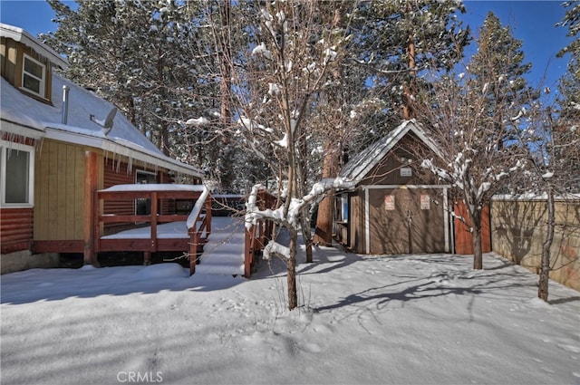 yard layered in snow with a wooden deck and an outbuilding