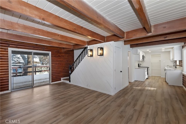 unfurnished living room with sink, wood ceiling, hardwood / wood-style flooring, rustic walls, and beamed ceiling