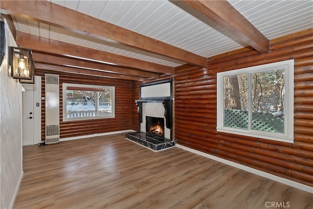 unfurnished living room with beamed ceiling, wood-type flooring, a fireplace, and log walls