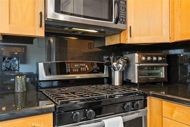 kitchen with gas range, dark stone counters, and decorative backsplash