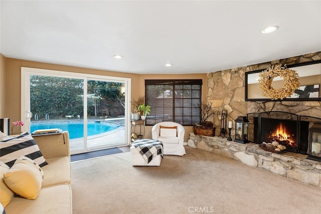 carpeted living room featuring a stone fireplace and a wealth of natural light