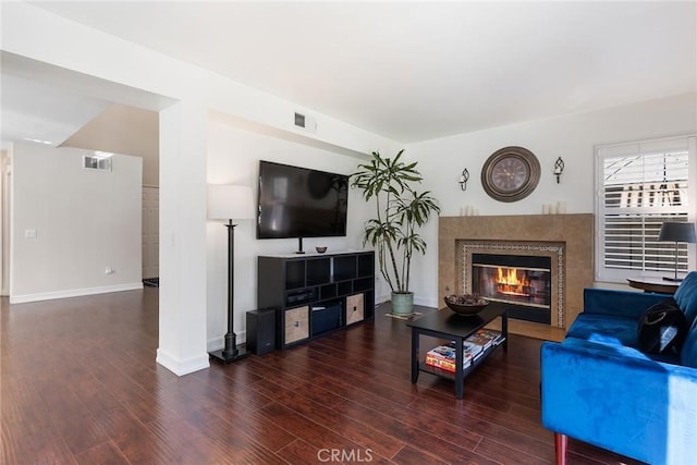 living room featuring a tile fireplace and dark hardwood / wood-style floors