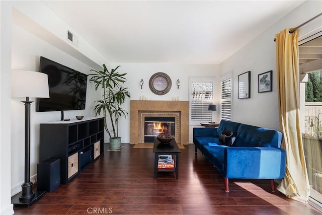 living room featuring a tile fireplace and dark hardwood / wood-style floors