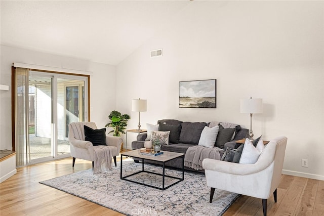 living room with light wood-style floors, baseboards, visible vents, and high vaulted ceiling