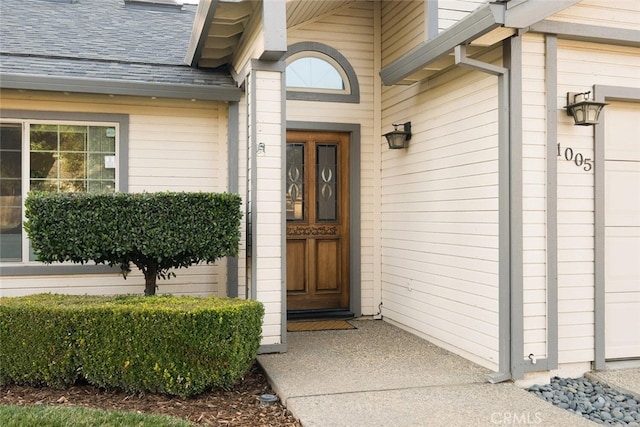 doorway to property with a shingled roof and an attached garage