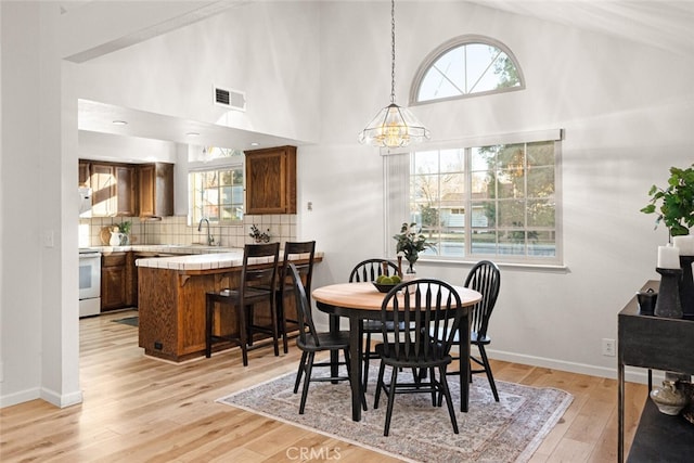 dining area with light wood-type flooring, visible vents, and a healthy amount of sunlight