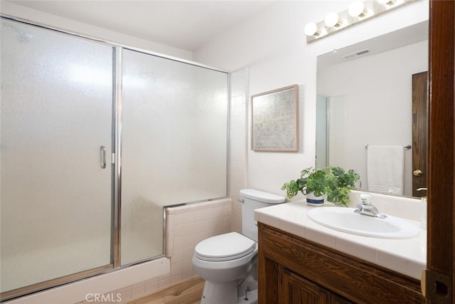 bathroom featuring visible vents, a shower with door, vanity, and toilet