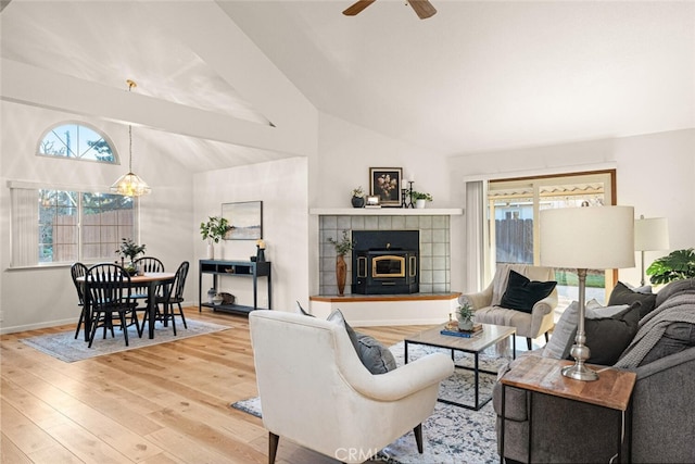 living area featuring lofted ceiling, ceiling fan with notable chandelier, wood-type flooring, and baseboards