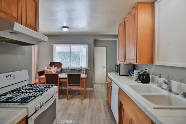 kitchen featuring white appliances, sink, and light wood-type flooring