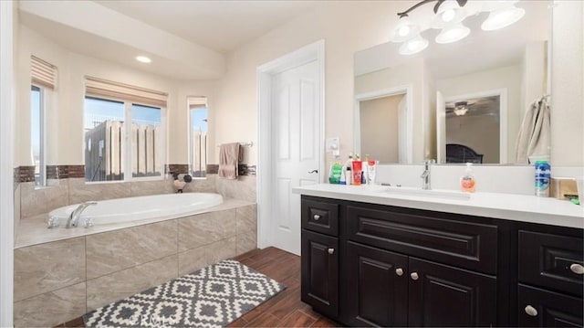 bathroom with vanity and tiled tub