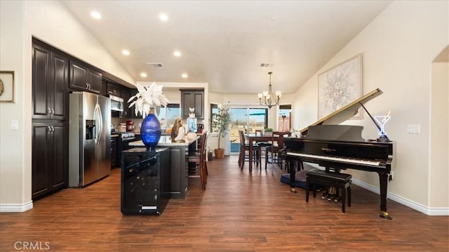 kitchen featuring appliances with stainless steel finishes, dark hardwood / wood-style floors, a breakfast bar area, hanging light fixtures, and a center island