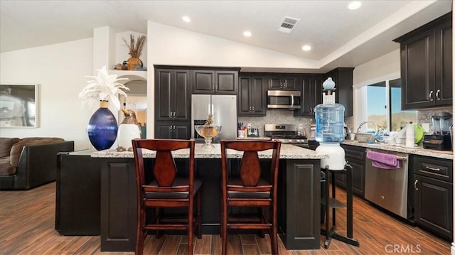 kitchen with visible vents, lofted ceiling, dark wood-style flooring, stainless steel appliances, and decorative backsplash