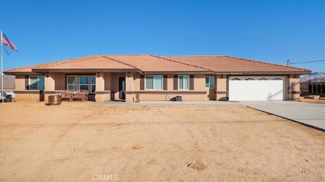 view of front of home featuring stucco siding, driveway, a tile roof, and a garage