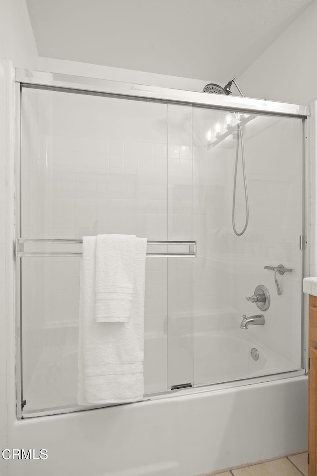 bathroom with tile patterned flooring and combined bath / shower with glass door