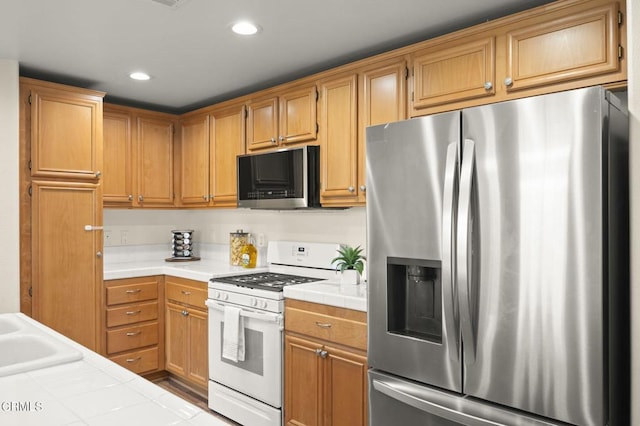 kitchen featuring stainless steel appliances, tile countertops, and sink