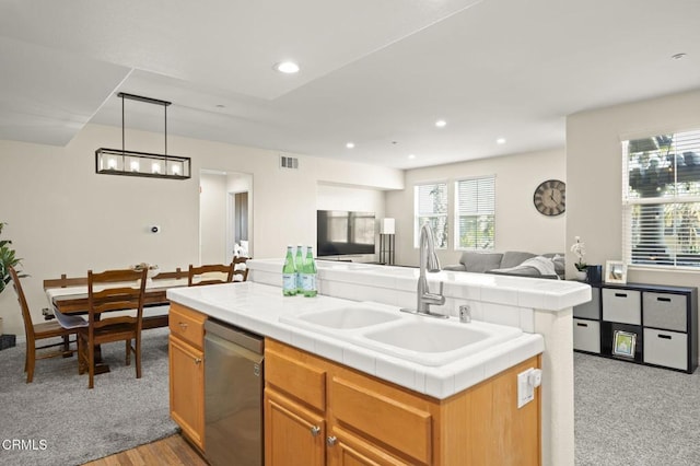 kitchen featuring pendant lighting, sink, a center island, stainless steel dishwasher, and tile counters