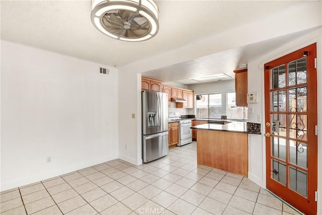 kitchen featuring white gas range, visible vents, a peninsula, under cabinet range hood, and stainless steel fridge with ice dispenser