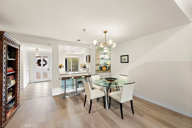 dining room featuring a notable chandelier, light hardwood / wood-style flooring, and sink