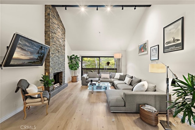 living room with light hardwood / wood-style flooring, a fireplace, high vaulted ceiling, and track lighting