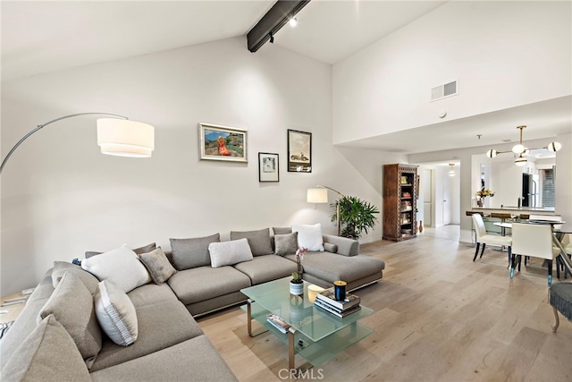 living room featuring beam ceiling, high vaulted ceiling, and light wood-type flooring