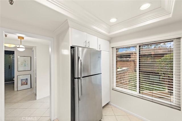 kitchen with light tile patterned floors, stainless steel fridge, ornamental molding, white cabinets, and a raised ceiling