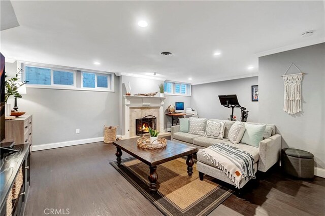 living room with ornamental molding, a tile fireplace, and dark hardwood / wood-style floors