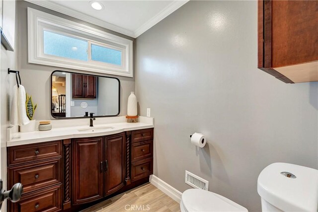 bathroom with crown molding, vanity, toilet, and hardwood / wood-style floors