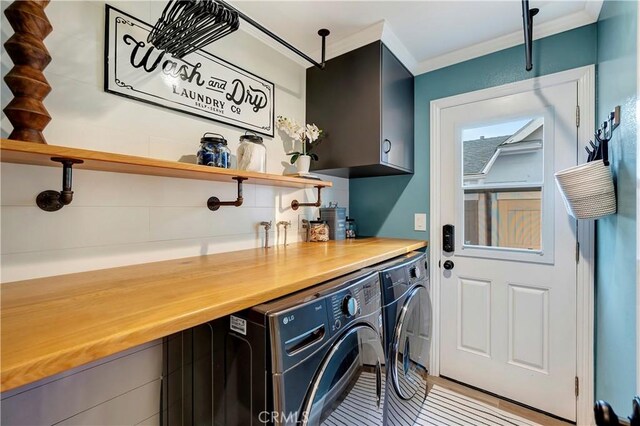 laundry room with washer and clothes dryer, ornamental molding, and cabinets