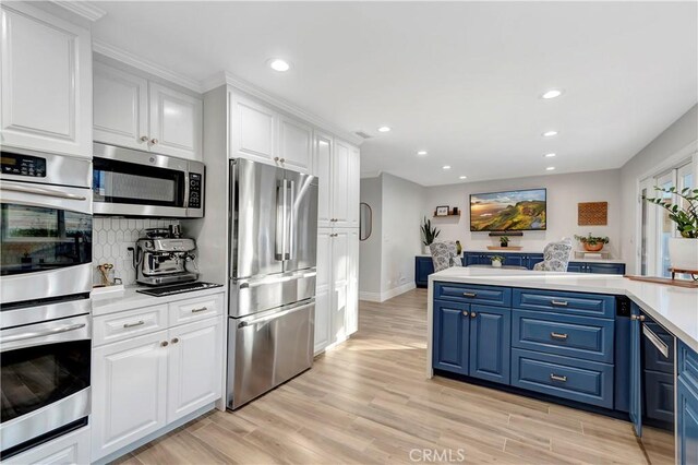 kitchen featuring light hardwood / wood-style flooring, stainless steel appliances, white cabinets, and blue cabinetry