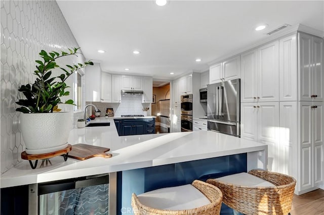 kitchen featuring sink, appliances with stainless steel finishes, a kitchen breakfast bar, kitchen peninsula, and white cabinets