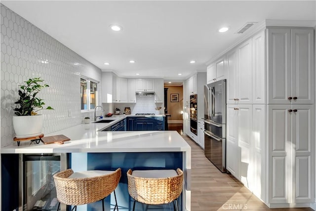 kitchen featuring blue cabinets, white cabinetry, sink, a kitchen breakfast bar, and stainless steel appliances