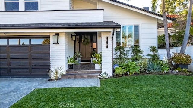 doorway to property with a garage and a lawn