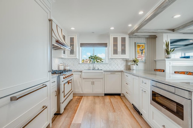 kitchen featuring stainless steel microwave, sink, high end white range, and white cabinets