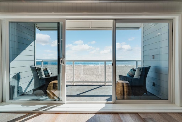 entryway with a view of the beach, hardwood / wood-style flooring, and a water view